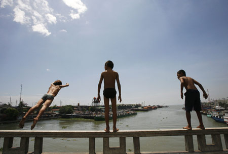 Children dive into polluted Manila bay to beat the simmering heat. The summer season officially started on the last week of February and is expected to end around the second week of May. [Xinhua/Reuters]