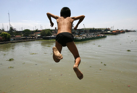 A boy dives into polluted Manila bay to beat the simmering heat March 18, 2009. The summer season officially started on the last week of February and is expected to end around the second week of May. [Xinhua/Reuters]