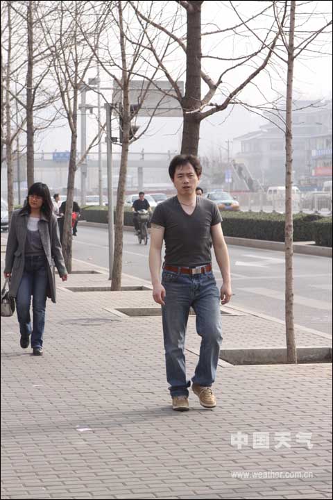 A man in T-shirt walks on a street in Haidian District of Beijing at noon March 18, 2009.