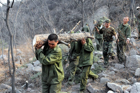 Soldiers set up a fireproof zone for a forest fire at Junying Village of Zanhuang County, north China's Hebei Province, March 18, 2009. The fire starting on March 16 has engulfed 26.7 hectares of forest by March 18. [Yang Shiyao/Xinhua]