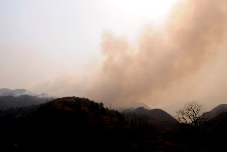 Photo taken on March 18, 2009 shows smoke rising from a forest fire at Junying Village of Zanhuang County, north China's Hebei Province. The fire starting on March 16 has engulfed 26.7 hectares of forest by March 18. [Yang Shiyao/Xinhua]