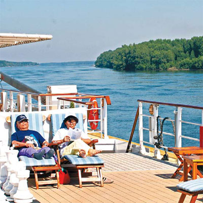 Tourists reading a book or napping in the sun while taking a cruise on the Danube.