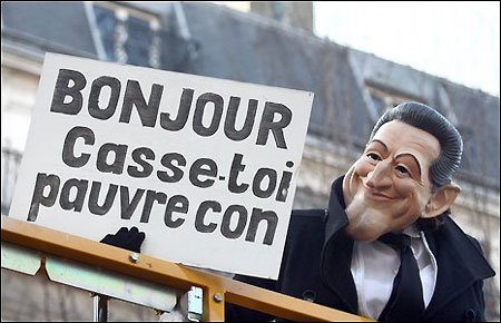 A protester in Paris dons a Sarkozy mask and holds a placard reading 'Hello - Beat it, loser' - words the president famously snapped at a hostile member of a crowd during a walkabout last year, March 18, 2009.[Agencies]