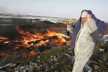 A worker stands near a fire destroying carcasses of swine infected with African swine fever after they were culled at a farm in the village of Kiyevka in the Stavropol region March 19, 2009. Veterinary workers killed some 200 animals to prevent the disease from spreading, officials said.[Xinhua/Reuters]