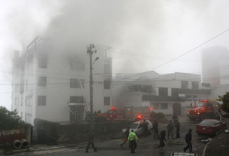 Firefighters spray water after a plane crashed on the roof a building in Quito March 19, 2009.[Xinhua/Reuters]