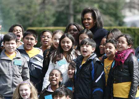 U.S. first lady Michelle Obama poses for a picture with 5th grade students from the Bancroft Elementary School during a groundbreaking ceremony for the new White House Kitchen Garden in Washington, March 20, 2009.[Xinhua/Reuters]