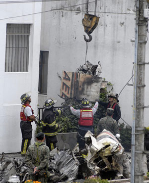 Ecuadoran firefighters clear wreckage of a crashed airplane in Quito, capital of Ecuador, Mar. 20, 2009. A small military plane hit part of one building in the northern part of the city before crashing into another building next to U.S. ambassador's residence in Quito on Thursday, killing seven people.[Xinhua]