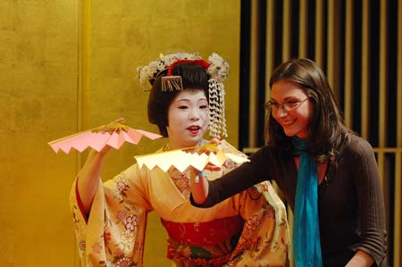 A foreign tourist follows a geisha to play a traditional Japanese game in Tokyo, capital of Japan, March 21, 2009. 