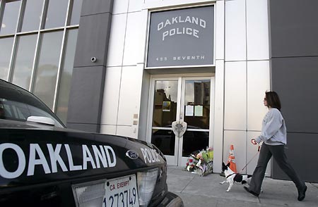 woman walks past a memorial of flowers in front of the Oakland police station in Oakland, California March 22, 2009. A man killed three police officers and critically wounded another on Saturday in two separate shootings that began with a traffic stop and ended with a gun battle, police said. 