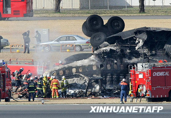 Emergency workers walk next to a crashed cargo plane at Narita international airport in Chiba, Japan March 23, 2009. [Xinhua/AFP]