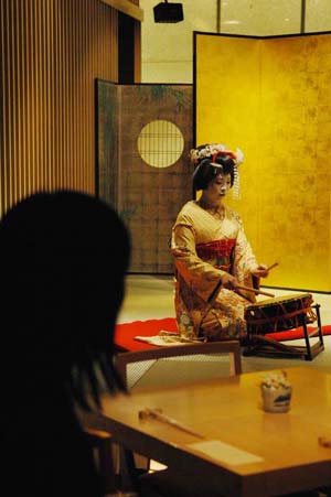 A tourist watches geisha's performance in Tokyo, capital of Japan, March 21, 2009. The Japanese government, with traditional art and unique culture of food to attract more and more foreign tourists, has planned to raise the number of foreign tourists visiting Japan to 20 million in 2020. [Sun Wei/Xinhua] 