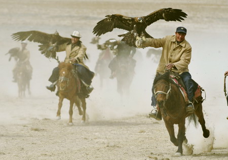 Falcon tamers ride horses during a hunting demonstration on the Second Falcon Cultural Festival in Akqi county, northwest China's Xinjiang Uygur autonomous region on March 21, 2009. [Xinhua]