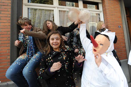 A reveller 'Blanc Moussi' (Clad in white) beats head of girls with pork bladders during carnival parade in Stavelot, about 150 kilometers east of Brussels, capital of Belgium, March 22, 2009. Carnival celebrations in Stavelot reached climax Sunday, while 'Blanc Moussi' flogged crowds with pork bladders and threw confetti to them. [Wu Wei/Xinhua]