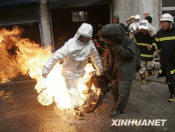 Firefighters carry out tanks of liquid gas out of a burning gas tank warehouse in downtown Luoyang, central China's Henan province, March 21, 2009. Over 70 firefighters fought the blaze for an hour, removing 81 compressed gas tanks out of the burning building. According to firefighters, the blaze was caused by an illicit operation of the gas tanks and a man had serious burn injuries. [Xinhua]