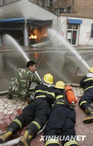 Firefighters use fire hoses to put out a fire at a gas tank warehouse in downtown Luoyang, central China's Henan province, March 21, 2009. [Xinhua]