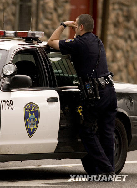An Oakland police officer pauses by his patrol car near the scene of a police involved shooting on MacArthur Boulevard where two police officers were shot, Saturday, March 21, 2009 in Oakland, Calif.[Xinhua/AP]