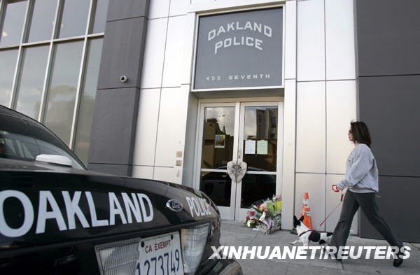 woman walks past a memorial of flowers in front of the Oakland police station in Oakland, California March 22, 2009. A man killed three police officers and critically wounded another on Saturday in two separate shootings that began with a traffic stop and ended with a gun battle, police said.[Xinhua/Reuters]