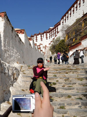 A visitor poses for photos at the Potala Palace in Lhasa, capital of southwest China's Tibet Autonomous Region, March 21, 2009. Lhasa, capital of southwest China's Tibet Autonomous Region, will be built into an international tourist city highlighting its unique plateau and ethnic characteristics. [Xinhua Photo] 