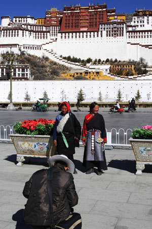 Two visitors pose for photos in front of the Potala Palace in Lhasa, capital of southwest China's Tibet Autonomous Region, Feb. 17, 2009. [Xinhua Photo]