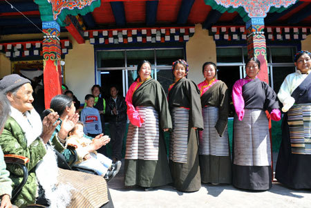 An elderly woman (1st L) who used to be a serf in Old Tibet applauds as other villagers dance at her house in a village in Qamdo, southwest China's Tibet Autonomous Region, March 22, 2009. [Xinhua photo] 