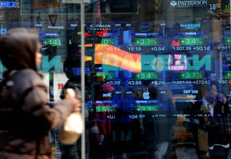 A woman passes by the NASDAQ electronic trading market on Times Square in New York, the United States, March 23, 2009. [Xinhua]