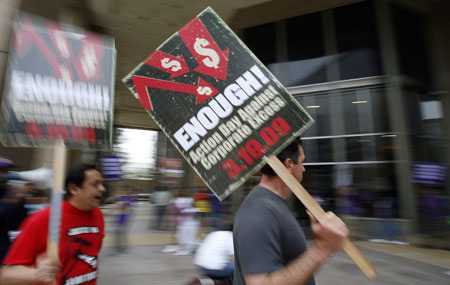 Protesters hold up signs as they rally outside the AIG building in Los Angeles March 19, 2009. The action was part of a national protest against major U.S. banks and firms with participants calling on Congress to take action on employee free choice, health care, and banking reform.[Xinhua/Reuters]