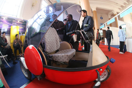 Visitors view an electric vehicle during the China International Energy Saving, Emission Reduction and New Energy Science and Technology Expo at the Beijing Exhibition Center in Beijing, capital of China, March 22, 2009. More than 200 companies and organizations took part in the five-day expo, opened on March 19. [Chen Xiaogen/Xinhua] 