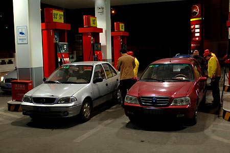 Staff members fill up some vehicles before the adjustment at a gas station in Beijing, China, Mar. 24, 2009. China said it would raise benchmark retail prices of gasoline and diesel by 290 yuan (42.46 U.S. dollars) per tonne and 180 yuan per tonne, respectively, as of midnight Tuesday. [Gong Lei/Xinhua]