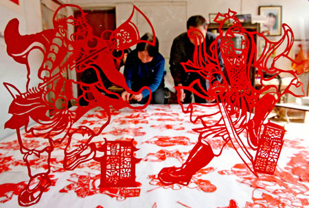 Folk artist Wang Zhenzhu displays her paper-cuttings of 108 generals of Chinese classic novel 'Outlaws of the Marsh', in Yuncheng, north China's Shanxi Province, March 24, 2009. It took Wang Zhenzhu some three months to finish the vivid paper-cuttings of aesthetic value. [Xue Jun/Xinhua] 