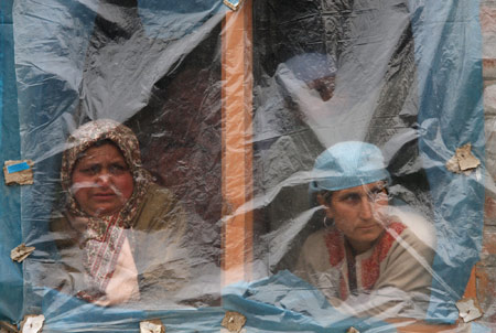 Women watch through a window during the funeral of Shabir Ahmad Malik, a Kashmiri Muslim soldier of the Indian army, in Dab, 35 kilometers north of Srinagar, summer capital of Indian-controlled Kashmir, March 24, 2009. 