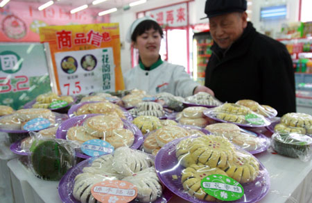 A shop employee introduces the Qingming pastry to a customer at a Daoxiangcun store in Beijing, capital of China, Mar. 24, 2009. Daoxiangcun, a time-honored foodstuff company in Beijing, produced a special pastry series for the upcoming Qingming Festival for Chinese people to pay respects to their ancestors. [Chen Xiaogen/Xinhua] 