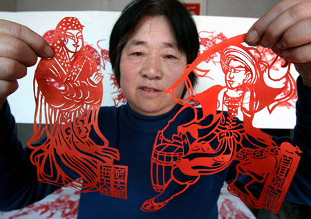 Folk artist Wang Zhenzhu displays her paper-cuttings of 108 generals of Chinese classic novel 'the Outlaws of the Marsh', in Yuncheng, north China's Shanxi Province, March 24, 2009. It took Wang Zhenzhu some three months to finish the vivid paper-cuttings of aesthetic value. [Xue Jun/Xinhua]