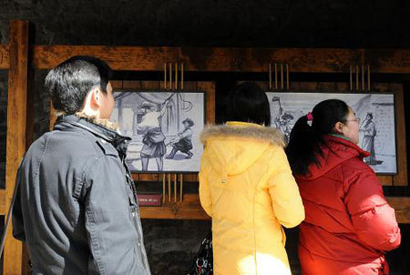 Visitors watch closely at the pictures at the Zhol City prison site at the foot of the Potala Palace. [Xinhua Photo]