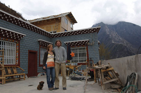 Owner of newly finished Tibetan-style Zhilam Hostel Kristopher Rubesh (R) and his wife Stephanie Rubesh (L) pose for photoes outside their hostel in Kangding, the Tibetan Autonomous Prefecture of Garze, southwest China's Sichuan Province, March 23, 2009. [Xinhua photo]