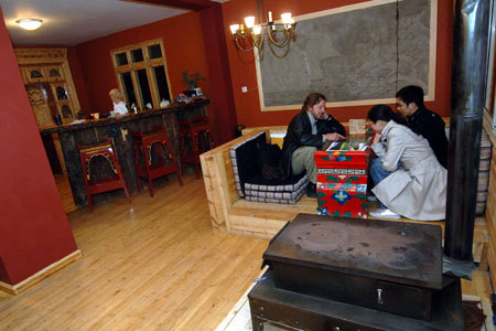 Owner of newly finished Tibetan-style Zhilam Hostel Kristopher Rubesh (1st L) introduces the places of interest in Kangding to guests in the lobby of his hostel in Kangding, the Tibetan Autonomous Prefecture of Garze, southwest China's Sichuan Province, March 23, 2009. [Xinhua photo]