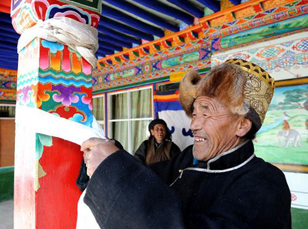 Losang Qambai, farmer of Jigu Village in Maizhokunggar County, southwest China's Tibet Autonomous Region (TAR), ties Hada (symbol of good luck in Tibet) to pillars of his new house on March 21, 2009. [Xinhua photo]
