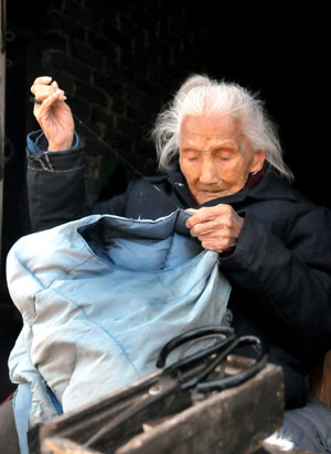 Lin Erde aged 106, mends clothes at Zhangkeng Village of De'an County, east China's Jiangxi Province, Mar. 24, 2009.[Xinhua]