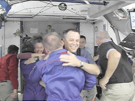 In this image from NASA Television, Wednesday, March 25, 2009, shuttle Discovery astronauts hug with international space station astronauts as they depart the ISS. Space shuttle Discovery has left the international space station. The shuttle undocked from the orbiting outpost Wednesday after eight days. Discovery and its crew of seven are due back Saturday. [Xinhua/AFP]