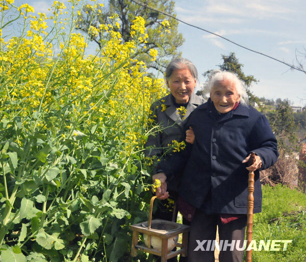 Lin Erde aged 106, supported by her elder daughter aged more than 80 with hands, strolls on the field at Zhangkeng Village of De'an County, east China's Jiangxi Province, Mar. 24, 2009. [Li Shibiao/Xinhua]