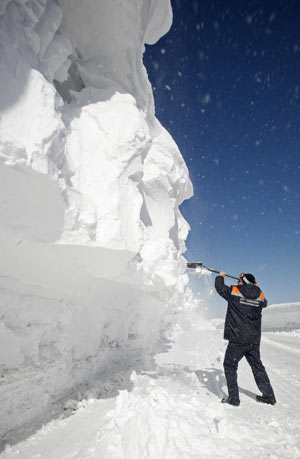 A rescuer clears snow on a highway from Krasnoyarsk to Mongolia after several avalanches on the Kulumys Pass in the Western Sayan Mountains some 620 km (385 miles) south of the Siberian city of Krasnoyarsk March 24, 2009.[Xinhua/Reuters]