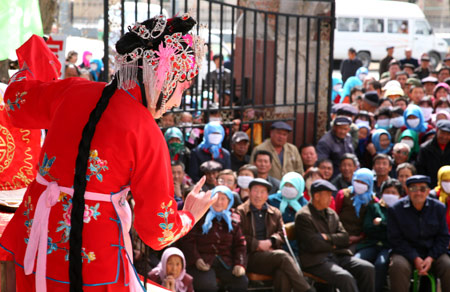 Local villagers watch the performance of the Qin Opera Art Troupe of Hami in Dahe Township of Barkol Kazak Autonomous County, northwest China's Xinjiang Uygur Autonomous Region, March 24, 2009. [Cai Zengle/Xinhua]