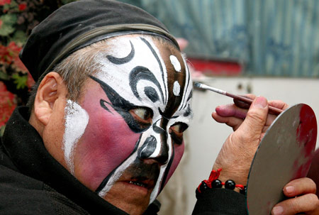 An actor of the Qin Opera Art Troupe of Hami makes up before getting on stage in a theater of Hami, northwest China's Xinjiang Uygur Autonomous Region, March 18, 2009. [Cai Zengle/Xinhua]