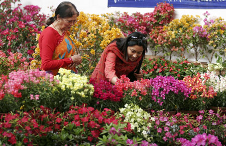 Women look at flowers during the 12th Floriculture Trade Festival-2009 in Kathmandu, capital of Nepal, on March 25, 2009. The five-day Festival started in Kathmandu on Wednesday. [Bimal Gautam/Xinhua]