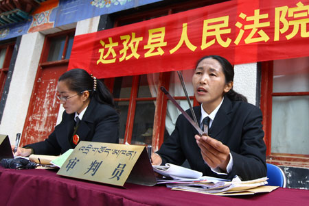 Judge Baizhen (R) attends a trial held by the mobile court at a village in Dagze County, southwest China's Tibet Autonomous Region, March 26, 2009. The court of Dagze County has dispatched the mobile court to villages for years to unload the economic burdens of those who entangled in lawsuits and popularize law knowledge among local residents. [Gong Bing/Xinhua]