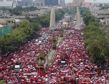 Supporters of former Thai Prime Minister Thaksin Shinawatra walk past the Democracy monument during a protest march to the Government House in Bangkok March 26, 2009. About 10,000 red-shirted protesters began their march from Sanam Luang to the Government House on Thursday, a local newspaper reported. [Xinhua/Reuters]