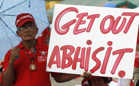 A supporter of former Thai Prime Minister Thaksin Shinawatra holds a sign during a rally at the Government House in Bangkok March 26, 2009.[Xinhua/Reuters]