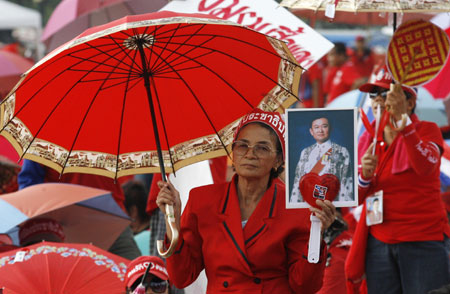  A demonstrator holds a portrait of former Thai Prime Minister Thaksin Shinawatra during a rally at the Government House in Bangkok March 26, 2009.[Xinhua/Reuters]