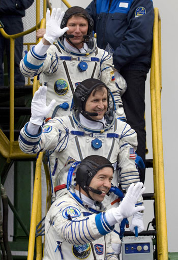 Russian cosmonaut Gennady Padalka (top), US entrepreneur Charles Simonyi (middle) and US astronaut Michael Barratt wave before entering a spacecraft at Baikonur Cosmodrome March 26, 2009. [China Daily/Agencies]