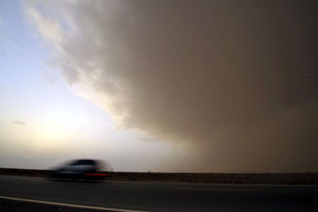 A car rushes on National Highway 314 at the north edge of the Tarim Basin in northwest China's Xinjiang Uygur Autonomous Region, March 26, 2009. Sandstorm hit the north part of the Tarim Basin on Thursday. [Shen Qiao/Xinhua] 