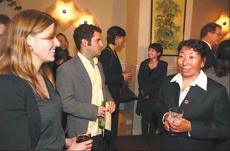 Kelsang Drolkar, head of Tama village in suburban Lhasa, Tibet, talks with Western guests at a buffet in Washington with assistants to the United States Congress on Mar 16. [Xinhua photo]